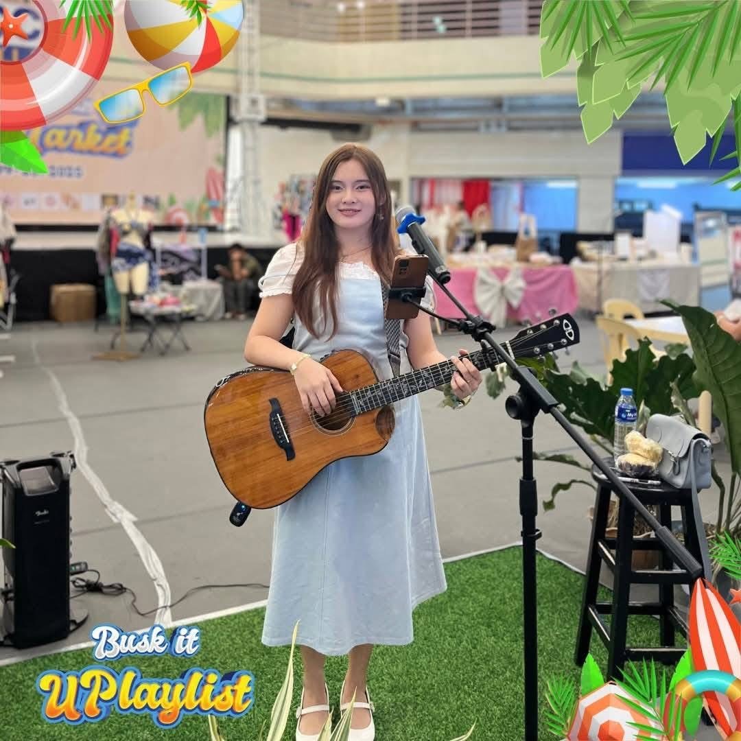 Kyla Jean busking with her acoustic guitar at a community bazaar